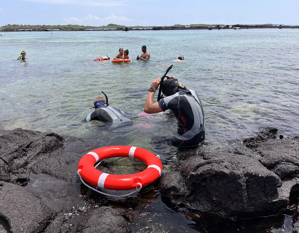 3_personas-haciendo-snorkeling-con-boya-roja-sobre-la-orilla-1